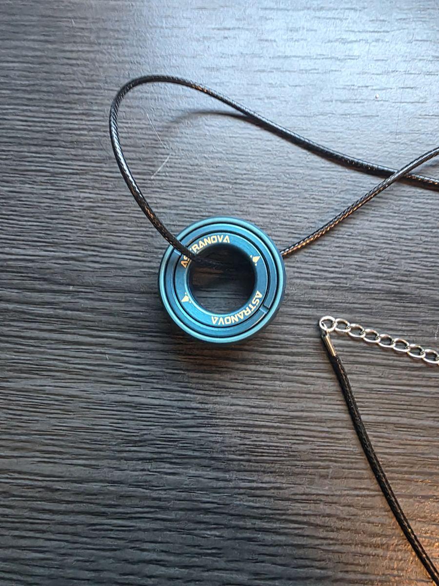 The Stellar Ring threaded on its black cord necklace