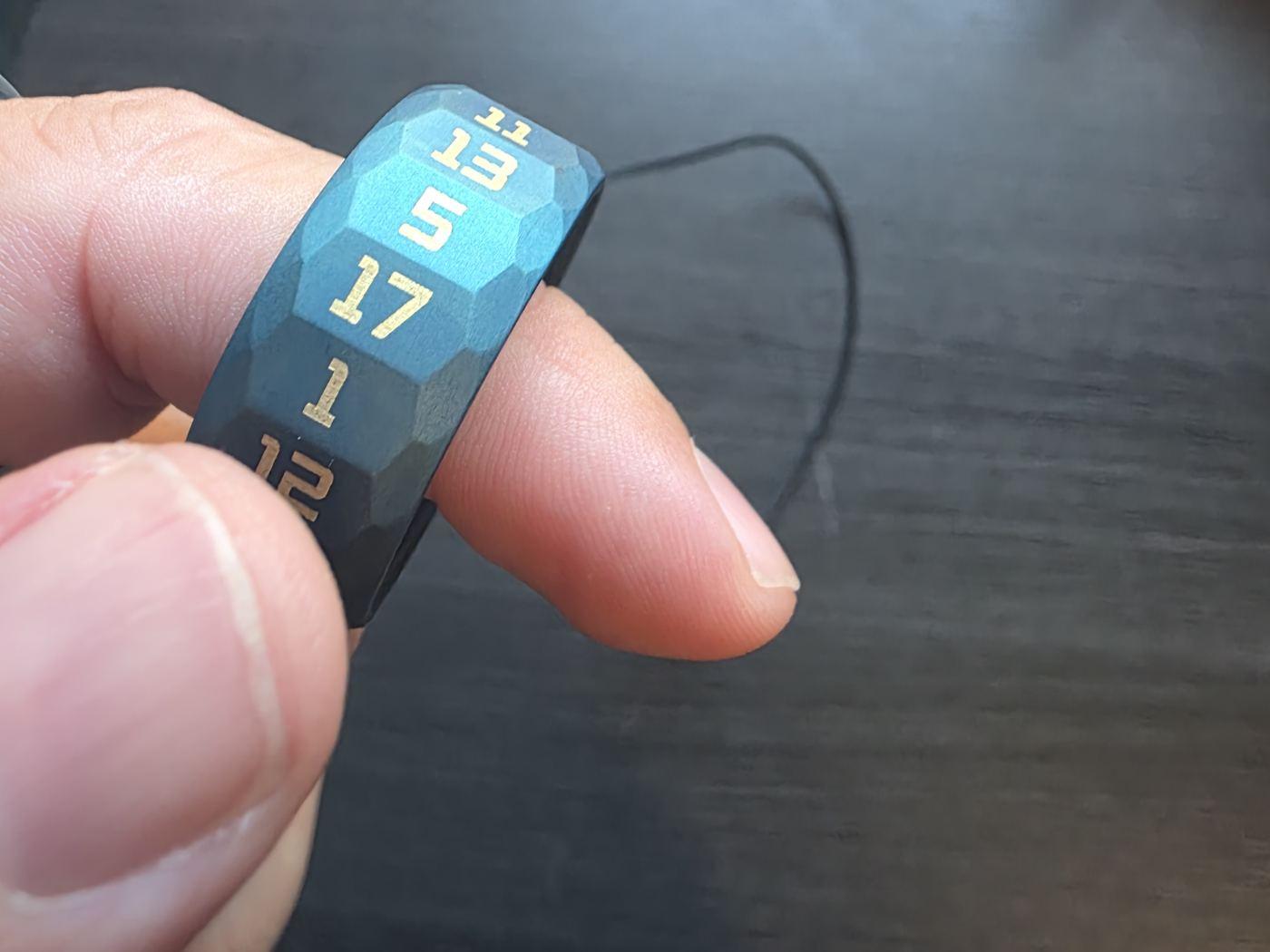 The blue Stellar Ring on a finger, gold numbers on its faceted faces