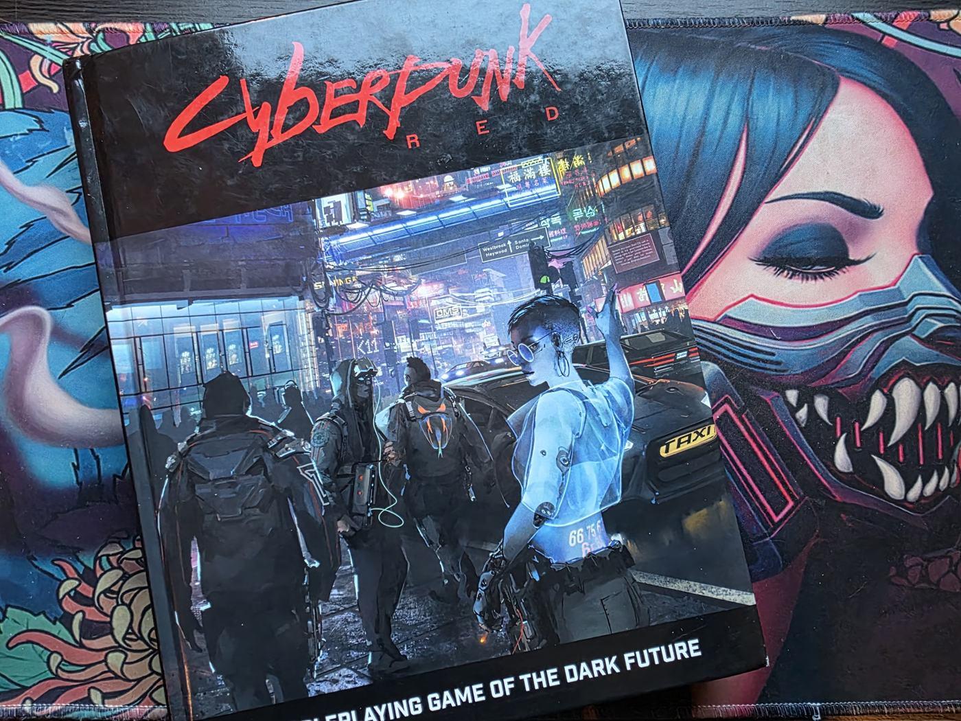 The Cyberpunk RED core rulebook lying on a neon-art playmat