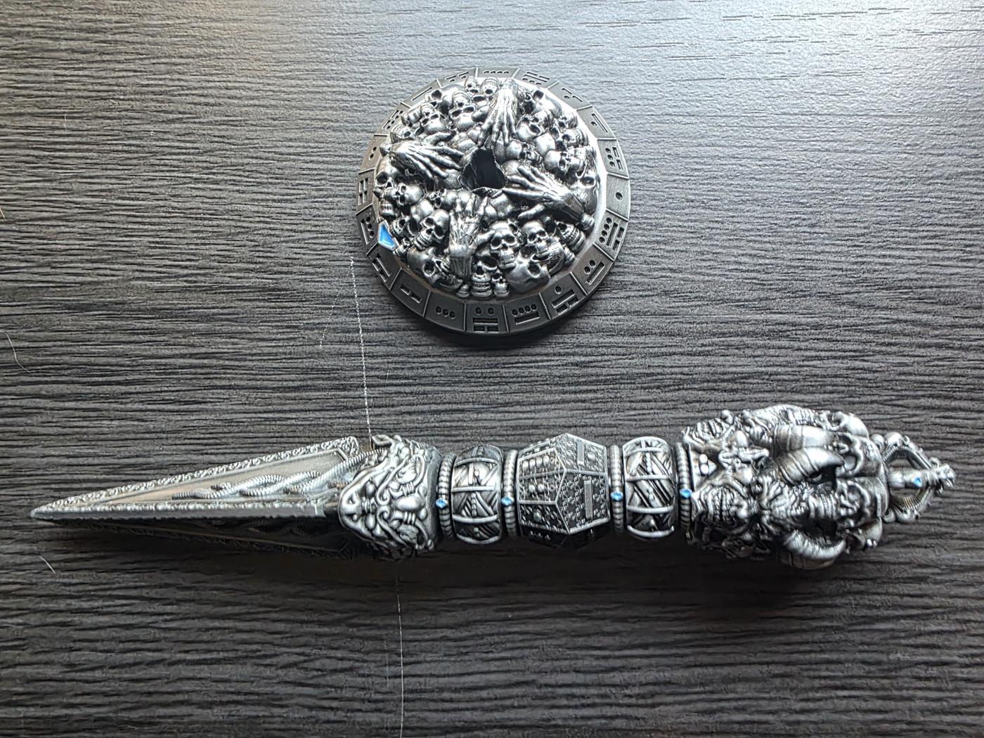 The Wand Dice dagger lying next to its skull-covered base, with dot-and-bar numbers around the base's rim
